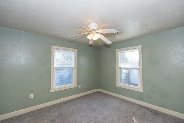 an empty room with windows and fan