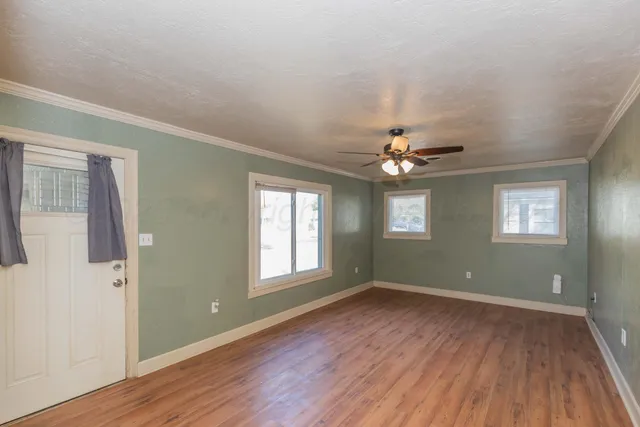 a view of empty room with wooden floor and fan