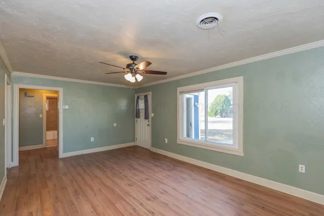 a view of an empty room with wooden floor and a window