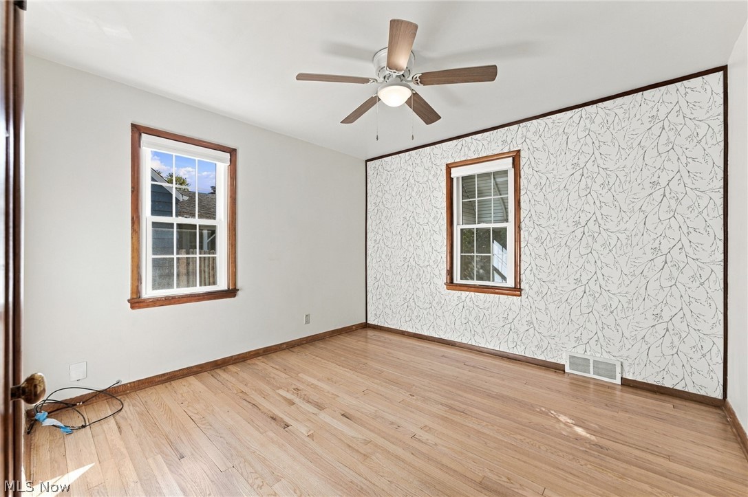1434 Sunset Road Mayfield Heights, OH 44124 - Photo 6 of 36 Hardwood flooring, white walls, and a decorative accent wall with a leaf pattern