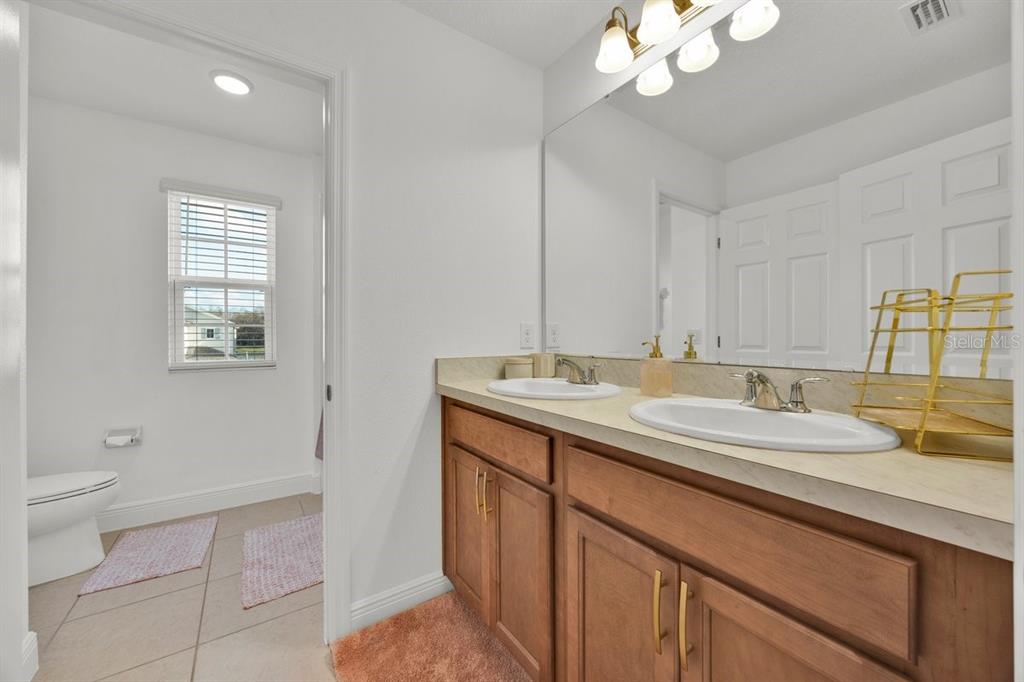 5237 Royal Point Avenue Kissimmee, FL 34746 - Photo 18 of 28 a bathroom with a granite countertop sink a toilet and a mirror