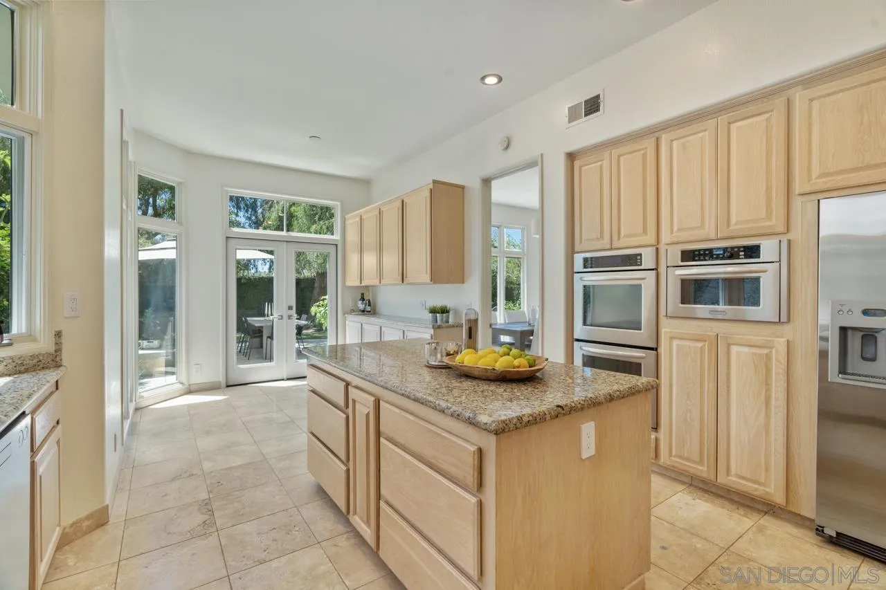9678 Claiborne Square La Jolla, CA 92037 - Photo 12 of 38 a kitchen with stainless steel appliances granite countertop a sink and a refrigerator