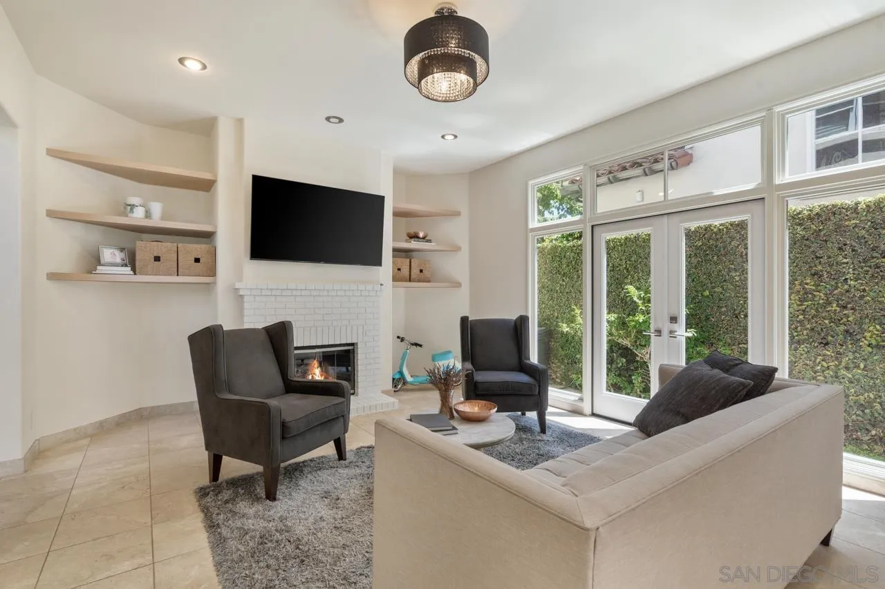 9678 Claiborne Square La Jolla, CA 92037 - Photo 16 of 38 a living room with furniture a flat screen tv and a floor to ceiling window