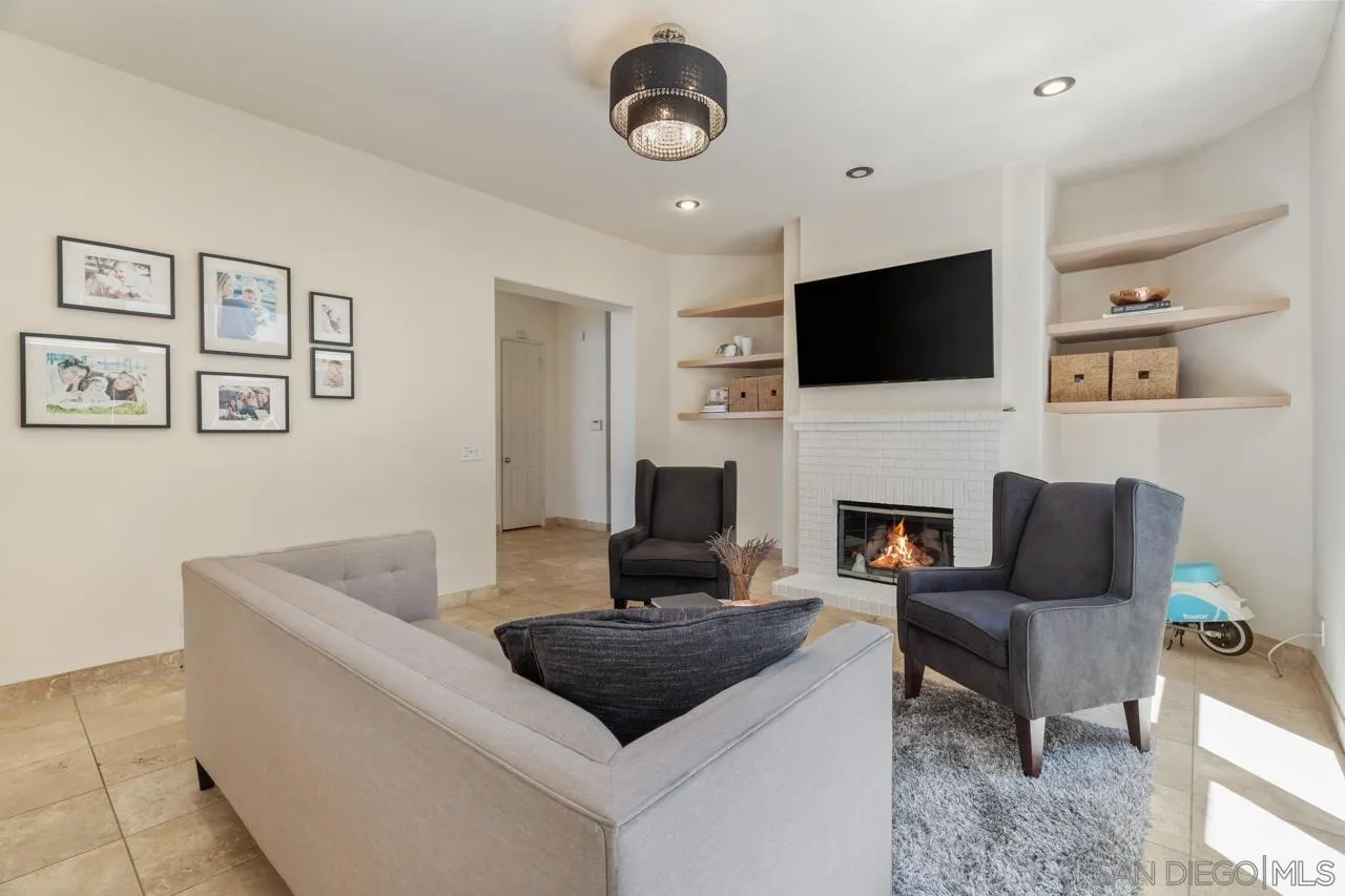 9678 Claiborne Square La Jolla, CA 92037 - Photo 17 of 38 a living room with furniture a fireplace and a flat screen tv