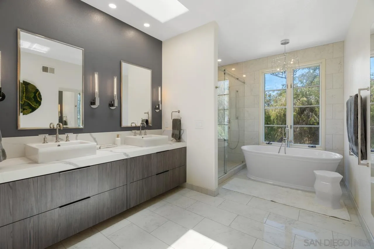 9678 Claiborne Square La Jolla, CA 92037 - Photo 24 of 38 a bathroom with a bathtub a double vanity sink a toilet a mirror and next to a window