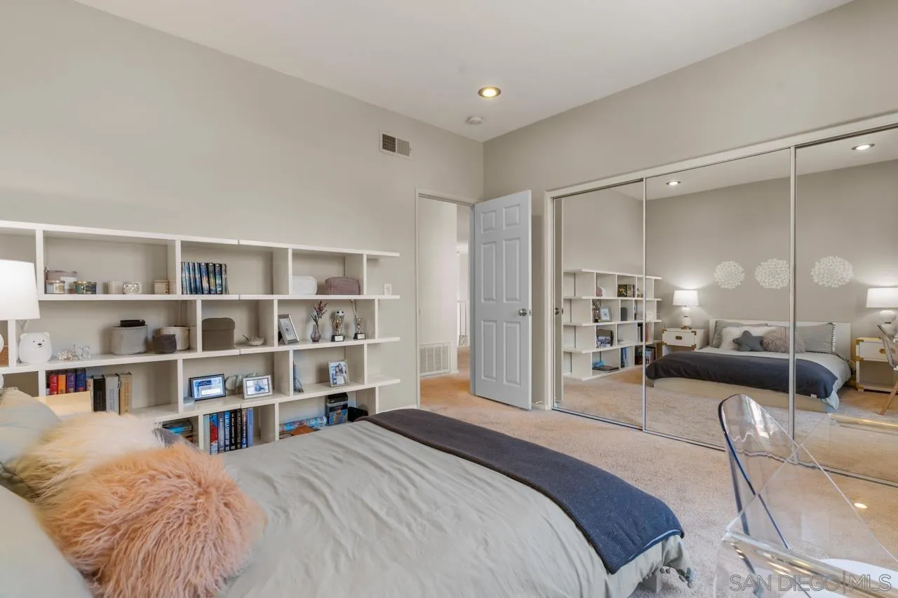 9678 Claiborne Square La Jolla, CA 92037 - Photo 30 of 38 a bedroom with a bed a table and a book shelf