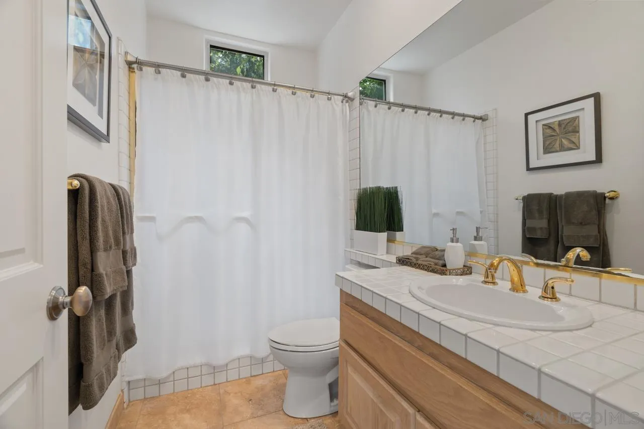 9678 Claiborne Square La Jolla, CA 92037 - Photo 33 of 38 a bathroom with a granite countertop sink toilet and shower
