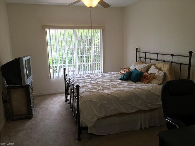 a bedroom with a bed a flat screen tv and window