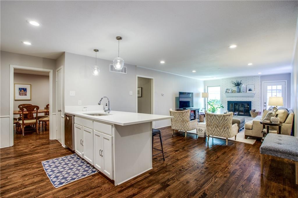 a large white kitchen with a stove a sink a dining table and chairs