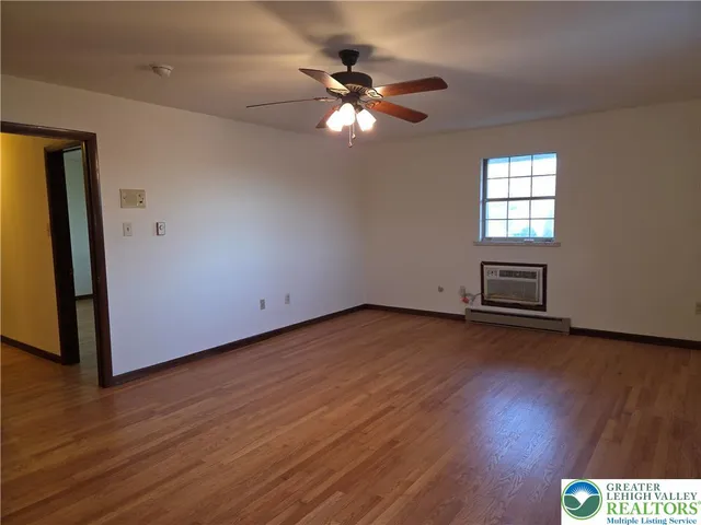 a view of empty room with wooden floor and fan