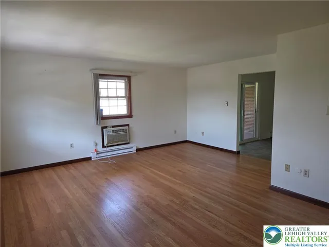 an empty room with wooden floor cabinet and windows