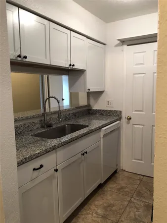 a kitchen with granite countertop a sink and cabinets