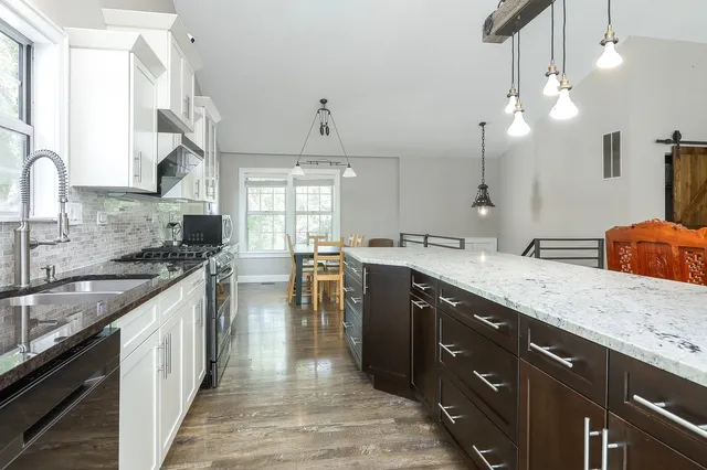 a large kitchen with granite countertop a sink a counter space appliances and cabinets