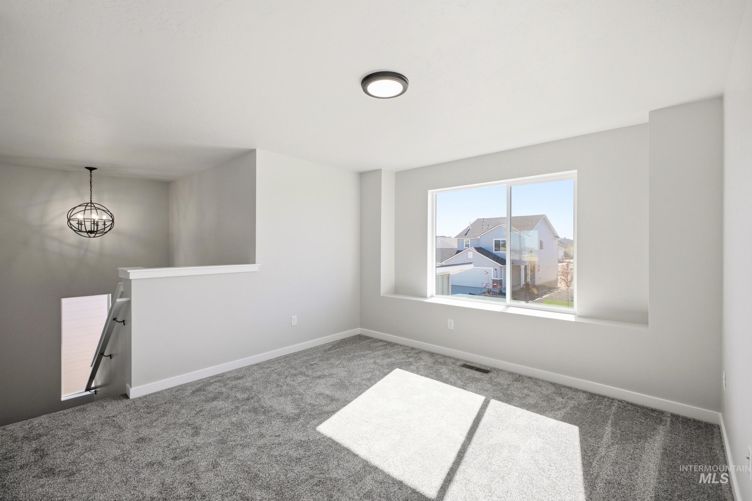 13325 Scrape Street Caldwell, ID 83607 - Photo 13 of 24 Carpeted flooring, contemporary flush-mount light fixture, large window with deep sill, staircase with railing, and spherical chandelier