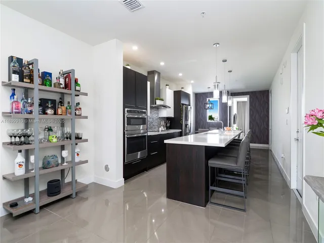 a kitchen with stainless steel appliances kitchen island granite countertop a refrigerator and a sink