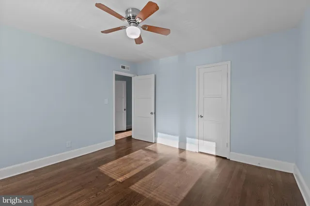 an empty room with wooden floor and a ceiling fan