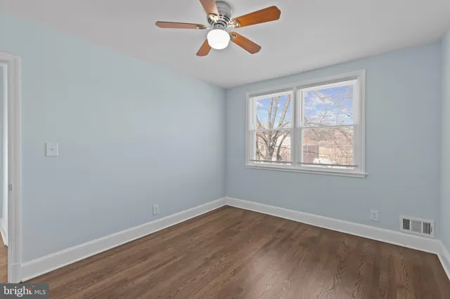 a view of an empty room with window and wooden floor