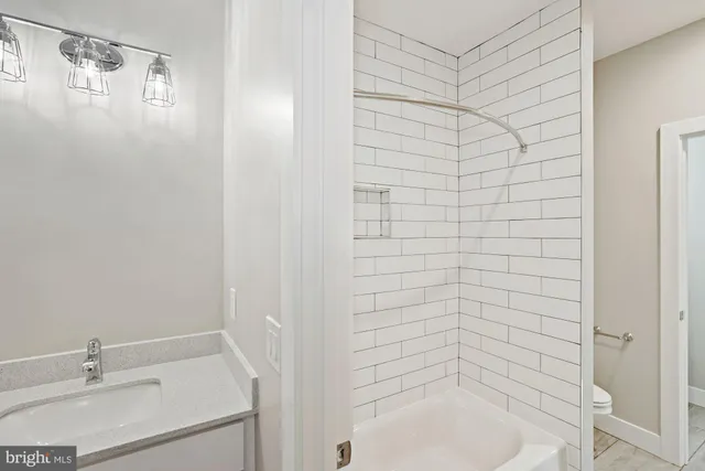 a bathroom with a sink and mirror with bathtub