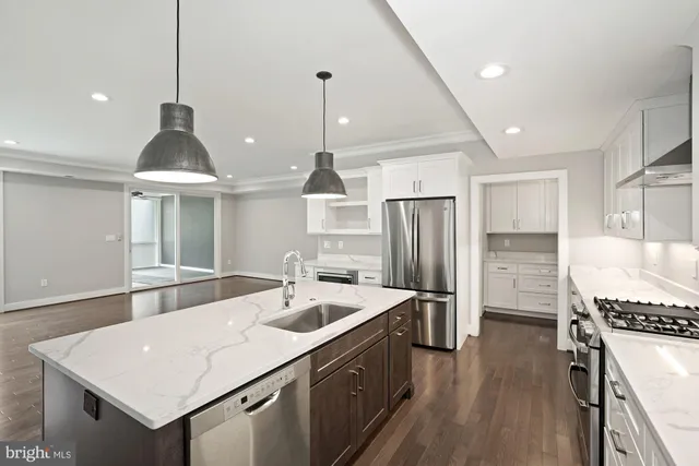 a kitchen with stainless steel appliances a sink a stove a refrigerator and island