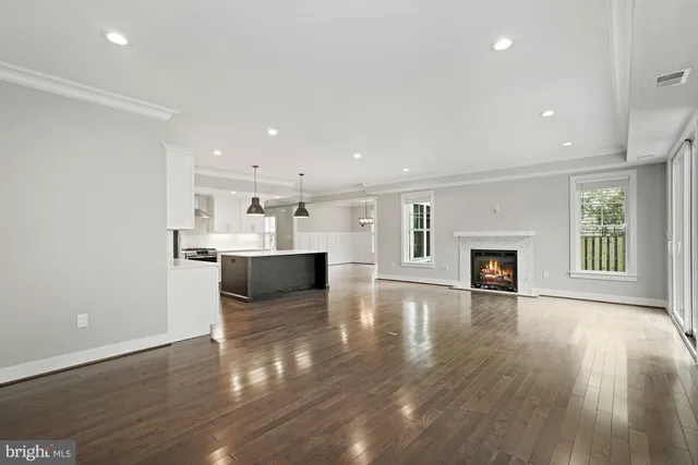 a view of an empty room with wooden floor and a fireplace
