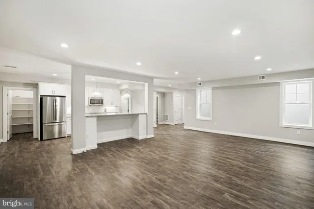 a kitchen with stainless steel appliances granite countertop a sink a stove a refrigerator cabinets and chairs