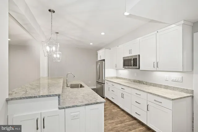 a kitchen with granite countertop a sink stove and refrigerator