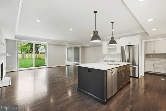 a view of a kitchen with kitchen island a sink wooden floor and a appliances