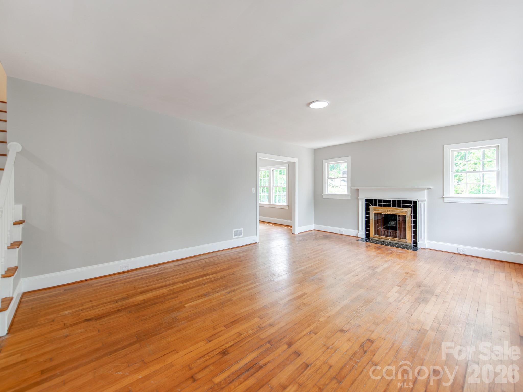 113 Falls Street Morganton, NC 28655 - Photo 4 of 33 an empty room with wooden floor and fireplace