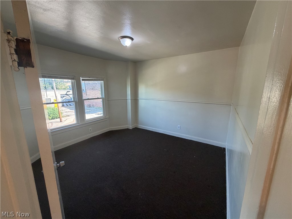 15300 Waterloo Road, Unit 1 Cleveland, OH 44110 - Photo 6 of 11 Interior room featuring dual windows, carpet flooring, a flush-mount ceiling light fixture, and two-tone wall finishes with chair rail detailing