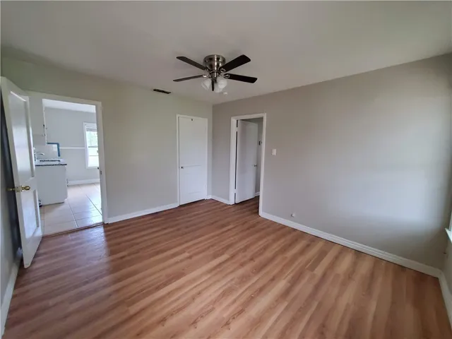 a view of empty room with wooden floor and fan