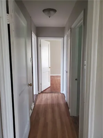 a view of a hallway with wooden floor and a bathroom