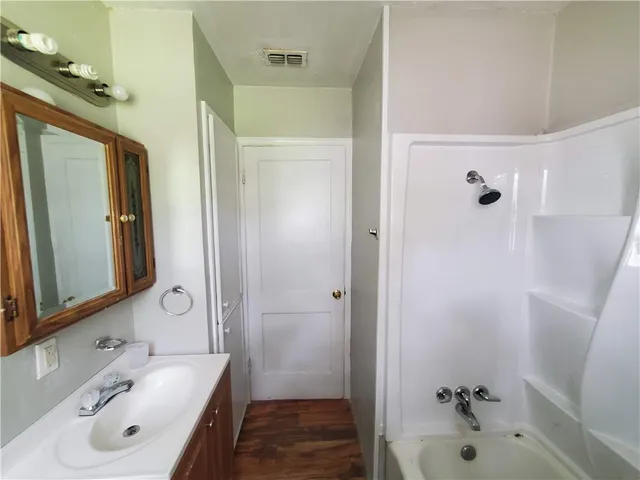 a bathroom with a tub sink vanity and mirror