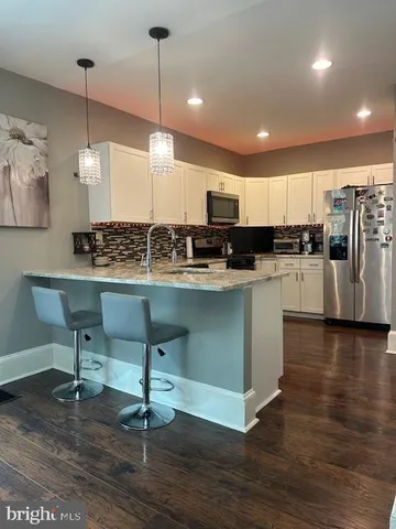 a kitchen with stainless steel appliances kitchen island granite countertop a sink a stove a dining table and chairs