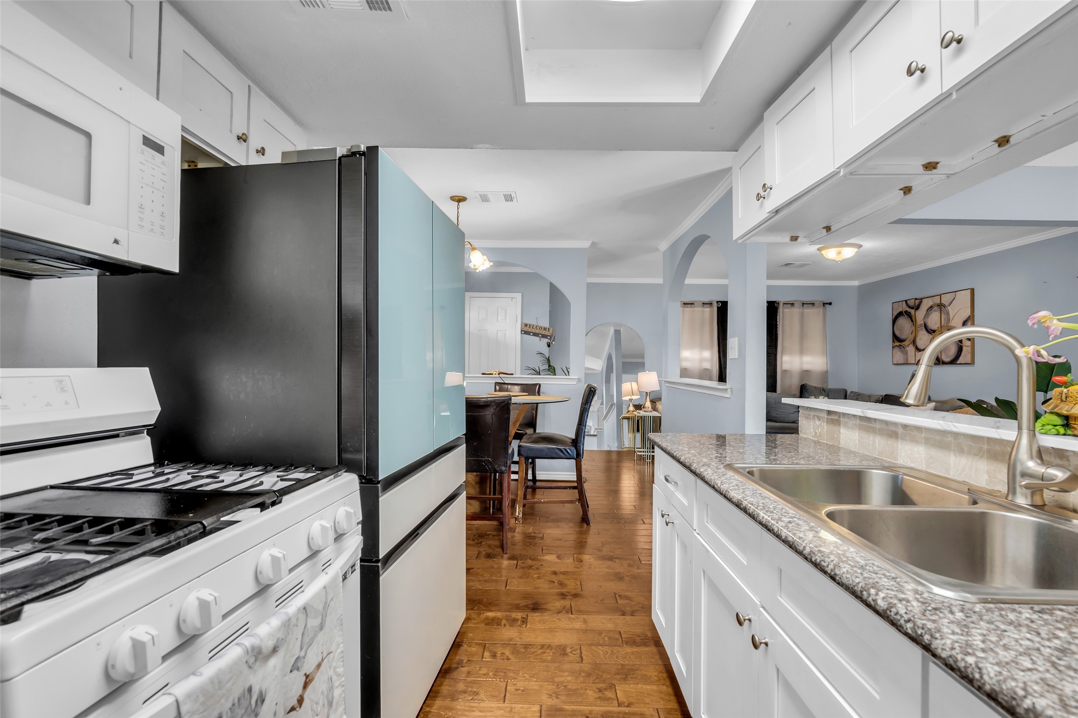 10730 Filey Lane Houston, TX 77013 - Photo 10 of 25 The open layout connects to a dining area and living space, featuring hardwood floors and soft lighting, creating a warm and inviting atmosphere.