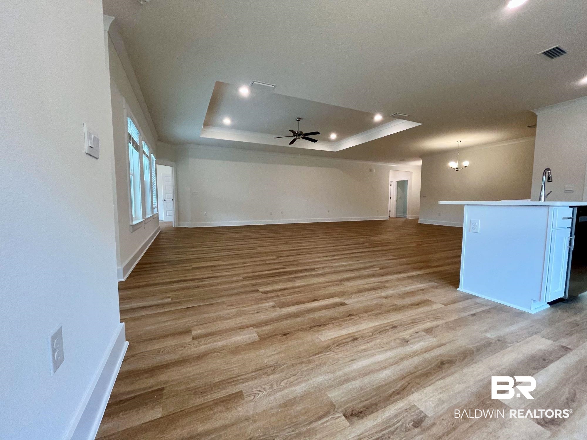 337 Barndling Street Fairhope, AL 36532 - Photo 16 of 34 Unfurnished living room featuring light hardwood / wood-style floors, ceiling fan with notable chandelier, and a raised ceiling