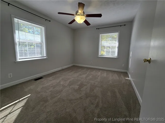 an empty room with windows and fan