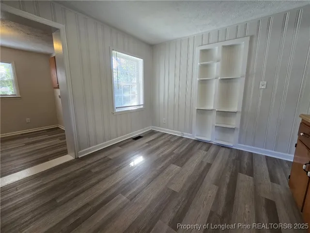 an empty room with wooden floor closet and windows