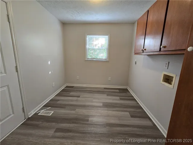 a view of an empty room with wooden floor and cabinets