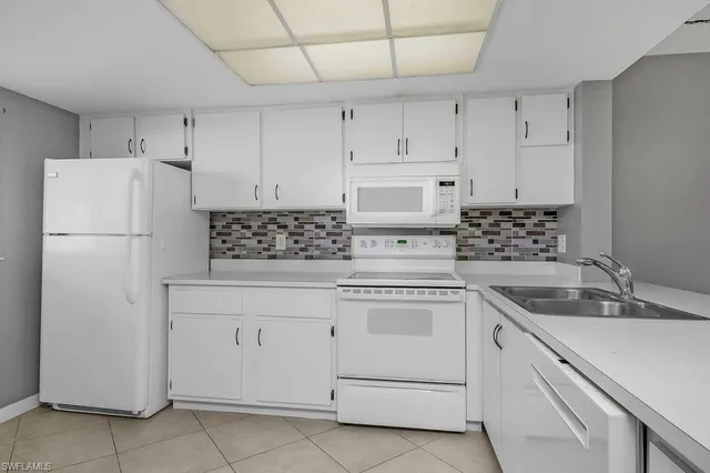 a kitchen with white cabinets and white appliances