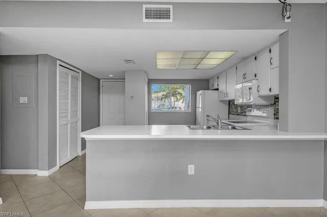 a view of a kitchen with kitchen island a sink stainless steel appliances and cabinets
