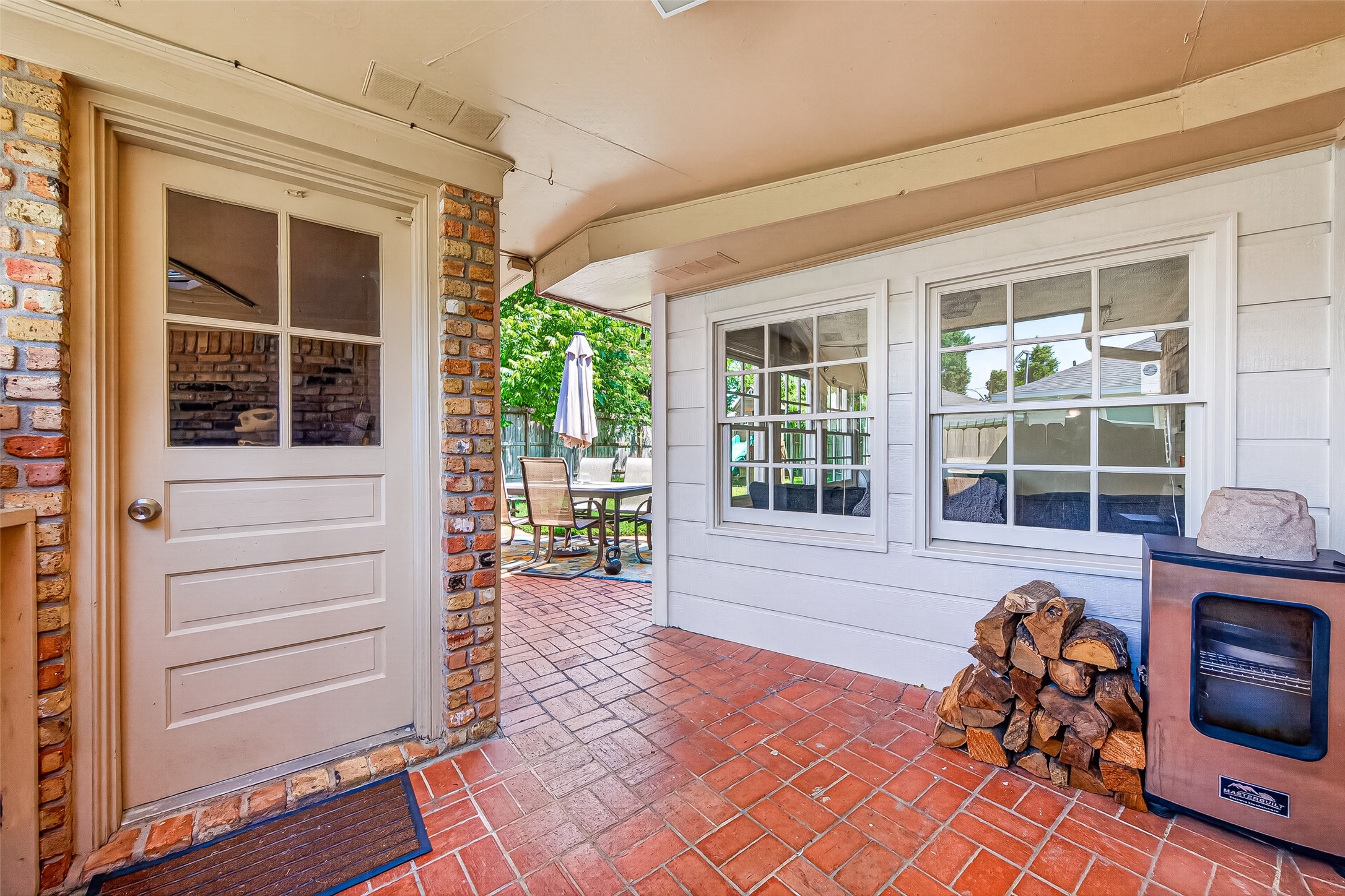 2610 Teague Road Houston, TX 77080 - Photo 42 of 49 This photo showcases a cozy patio area with brick flooring, a side door, and large windows providing natural light.