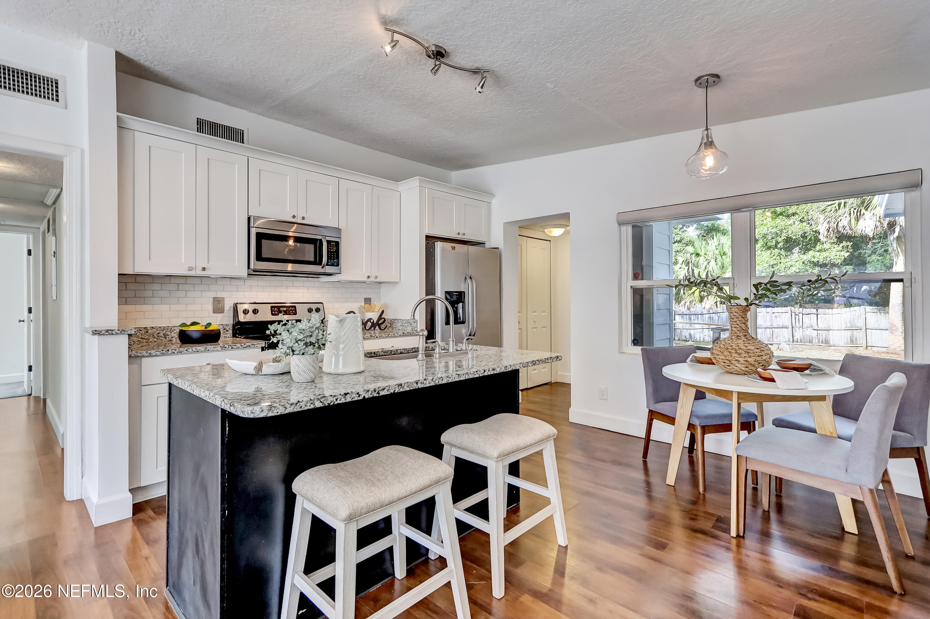 2477 Community Road Jacksonville, FL 32207 - Photo 5 of 33 a kitchen with kitchen island granite countertop a table chairs microwave and cabinets