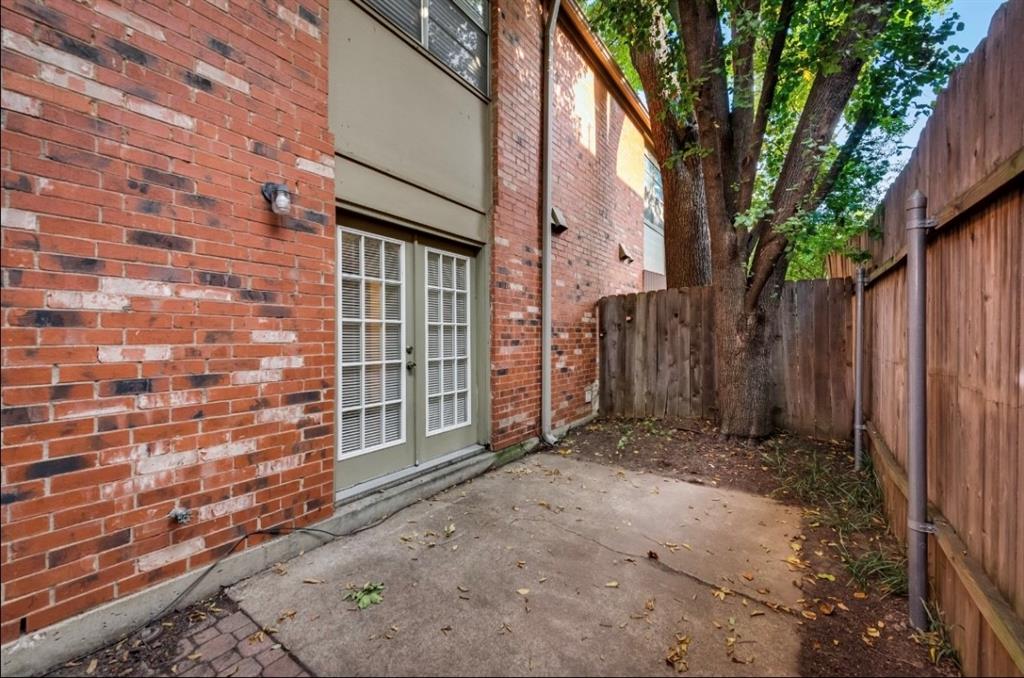 a view of backyard with brick wall and a large tree