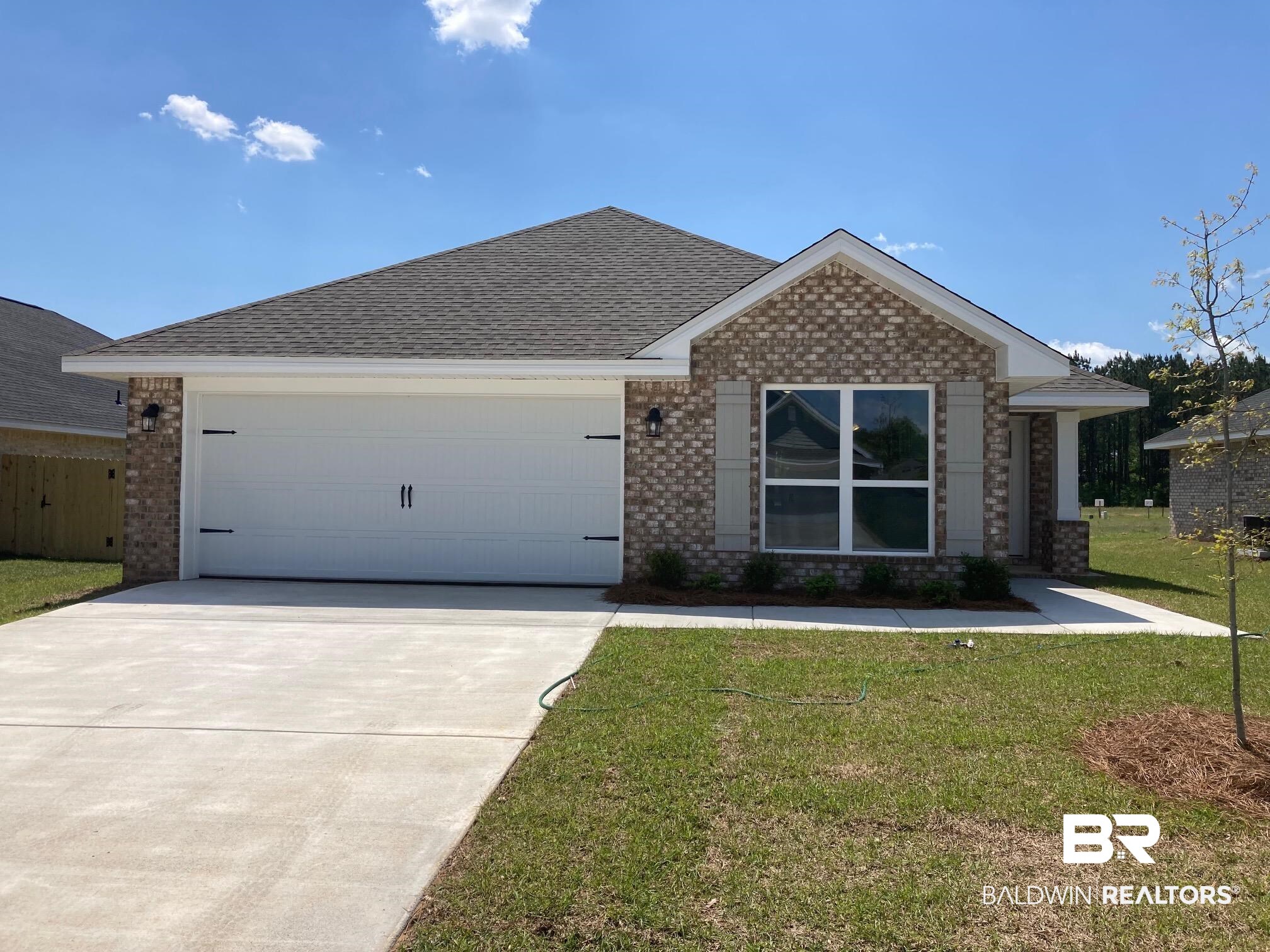 662 Revere Street Foley, AL 36535 - Photo 1 of 1 Ranch-style house featuring roof with shingles, a front lawn, brick siding, an attached garage, and concrete driveway