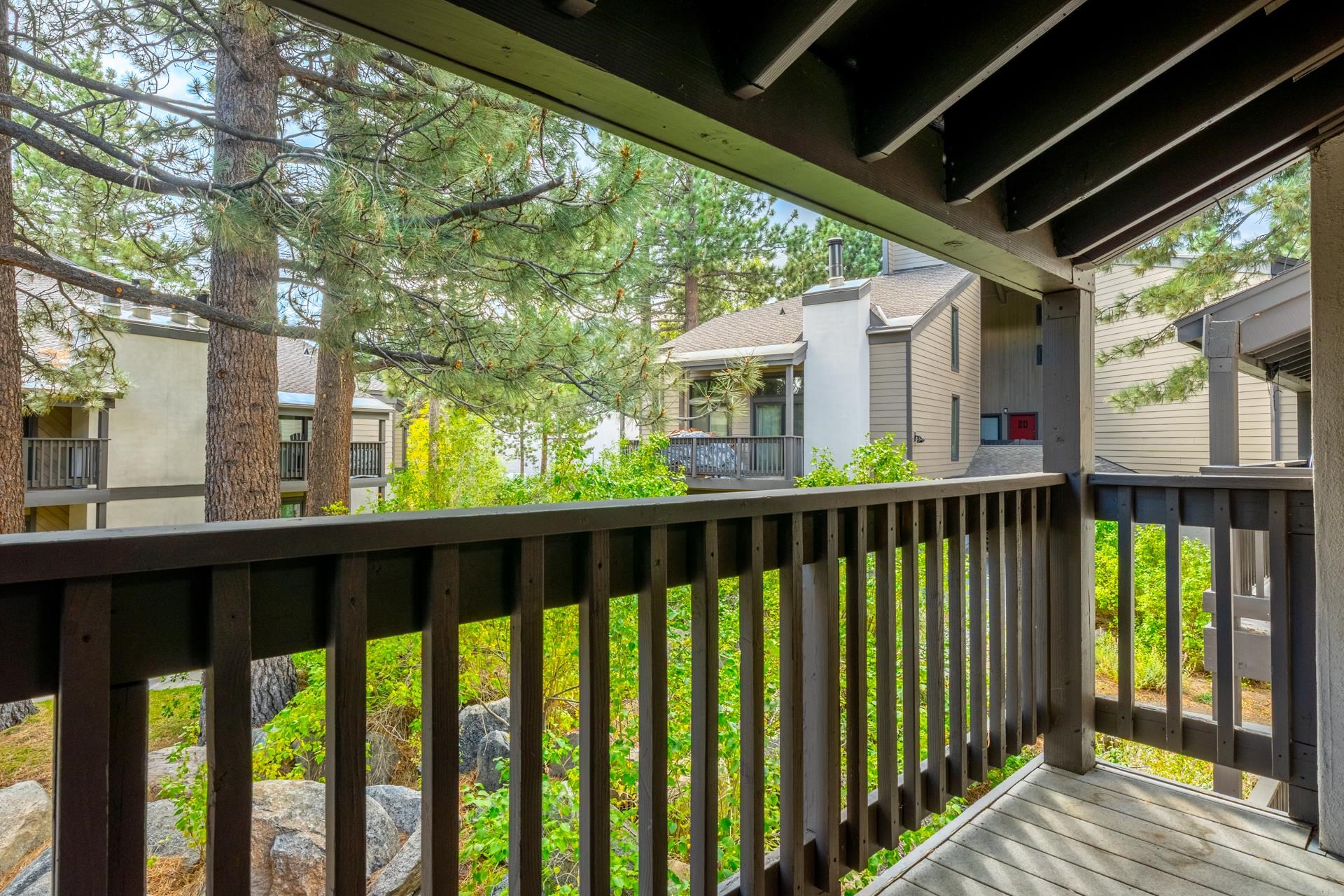 362 Old Mammoth Road, Unit 59 Mammoth Lakes, CA 93546 - Photo 27 of 35 Covered wood-plank balcony with dark wood railing, surrounded by mature trees