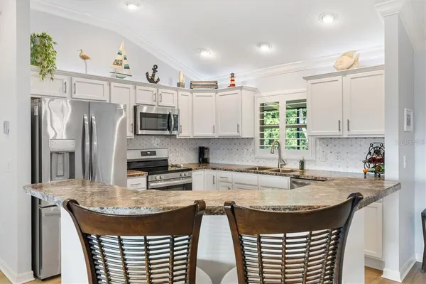 a kitchen with kitchen island granite countertop a sink a center island and stainless steel appliances