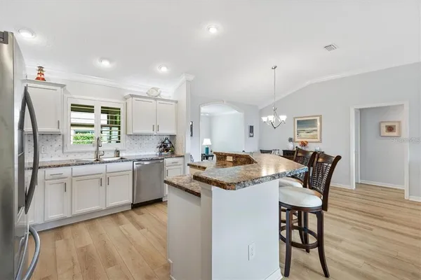 a kitchen with stainless steel appliances granite countertop a table chairs sink and stove top oven