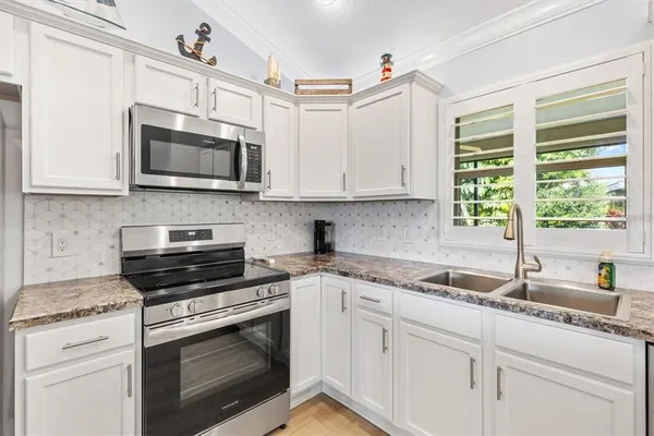a kitchen with stainless steel appliances granite countertop white cabinets granite counter tops and a window