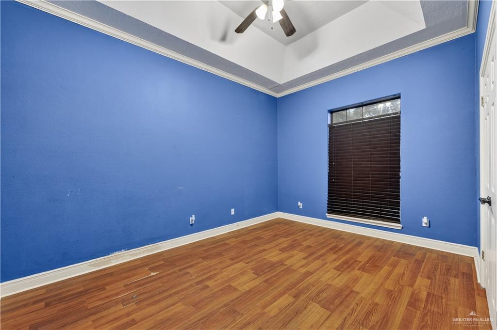 6004 North Cynthia Street McAllen, TX 78504 - Photo 16 of 25 Room featuring wood-finish flooring, a tray ceiling with crown molding, and a ceiling fan with light fixture