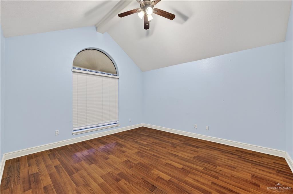 6004 North Cynthia Street McAllen, TX 78504 - Photo 17 of 25 Vaulted ceiling room featuring a large arched window with blinds, wood-finish flooring, and a ceiling fan